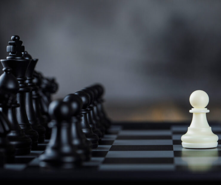 Business strategy concept with figures on chessboard on foggy and wooden background side view.