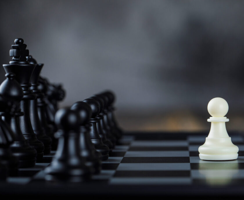 Business strategy concept with figures on chessboard on foggy and wooden background side view.